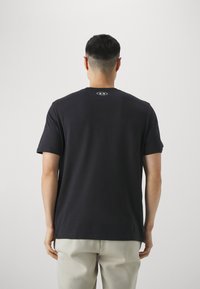 Sort kortærmet t-shirt lavet af blødt bomuld med rund halsudskæring og et lille logo trykt på ryggen. Glat tekstur og afslappet pasform.