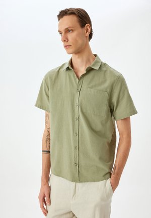 Korte mouwen lichtgroen shirt van gestructureerde stof, met een knoopsluiting aan de voorkant en een enkele borstzak. Rechte snit.