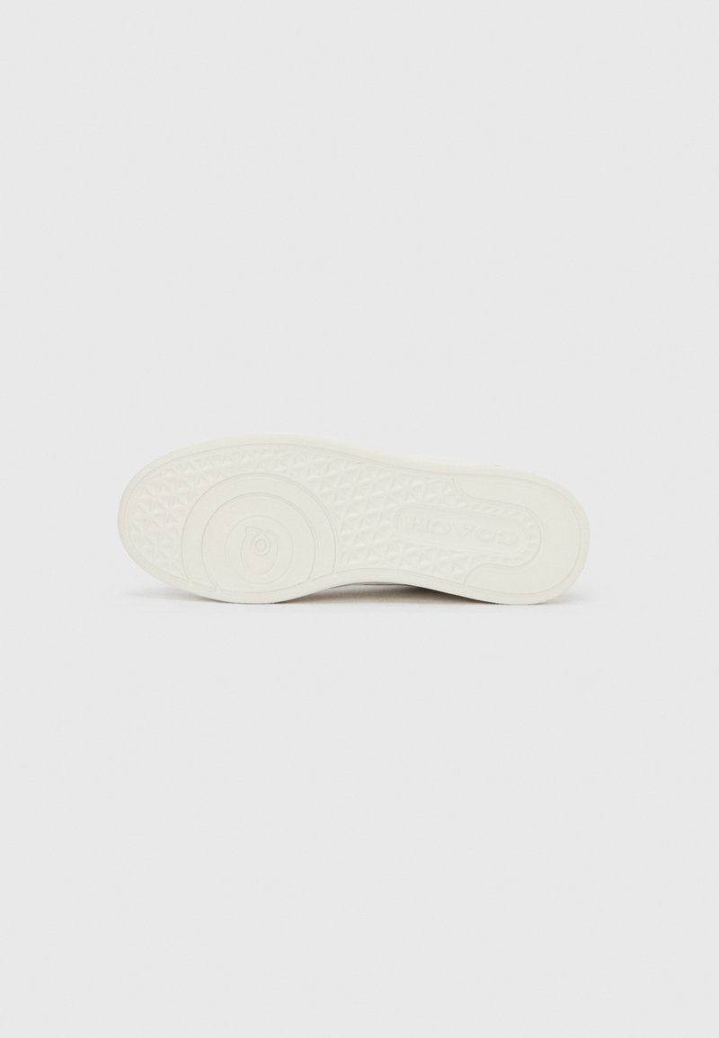 Semelle de chaussure en caoutchouc blanc avec motif de grip texturé, comportant un détail de logo rond, design plat, sans marque visible sur la face inférieure.