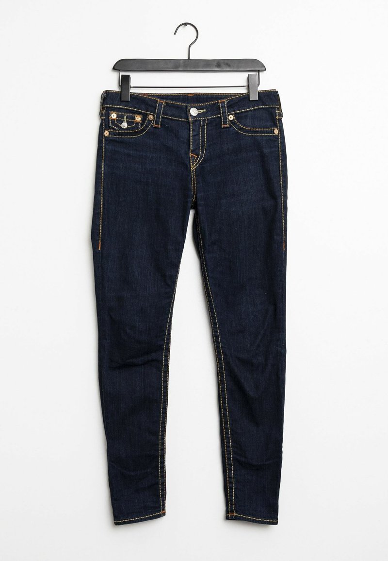 Jean en denim bleu foncé avec coutures orange suspendu sur un cintre en plastique noir sur fond blanc.