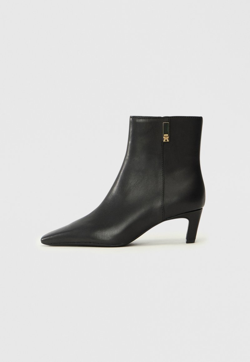 Sorte lær ankle boot med spiss tå og en liten hæl. Har glidelås på siden med en gullfarget detalj. Glatt tekstur.
