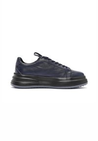 Zapatillas de cuero en azul marino oscuro con una textura suave, que presentan una puntera redondeada, acentos en negro y una suela de goma gruesa para mayor altura.