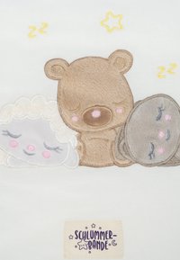 Gesticktes Design mit einem schlafenden Bären, Schafen und einem Felsen auf einem hellen Hintergrund, in Pastellfarben, mit einem Etikett, das "SCHLUMMER-BANDE" liest.