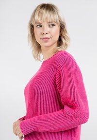 Helles pinkes Rippstrick-Pullover mit langen Ärmeln, der subtile blaue Akzente entlang der Nähte und einen klassischen Rundhalsausschnitt aufweist.