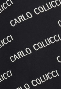 Fekete kötött anyag, amelyen folyamatosan ismétlődő fehér szöveg olvasható: "CARLO COLUCCI", jellegzetes, vastag betűtípussal.