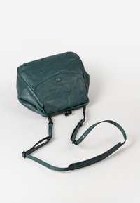Zaino in pelle turchese dalla forma arrotondata, con patta frontale, chiusura a scatto, spallacci regolabili e superficie liscia. Design minimalista senza motivi.