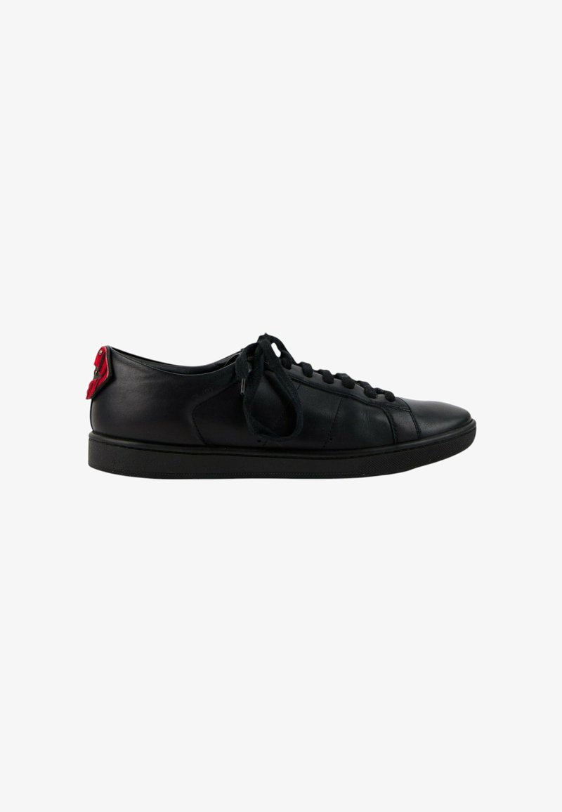 Baskets basses en cuir noir avec des lacets noirs et un détail rouge au talon, présentées de profil sur un fond blanc.