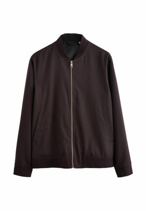 Tummanruskea bomber-jacket, jossa on vetskari edessä, ribbireunus kauluksessa ja hihoissa. Takissa on kaksi sivutaskua ja sileä, matta pinta.