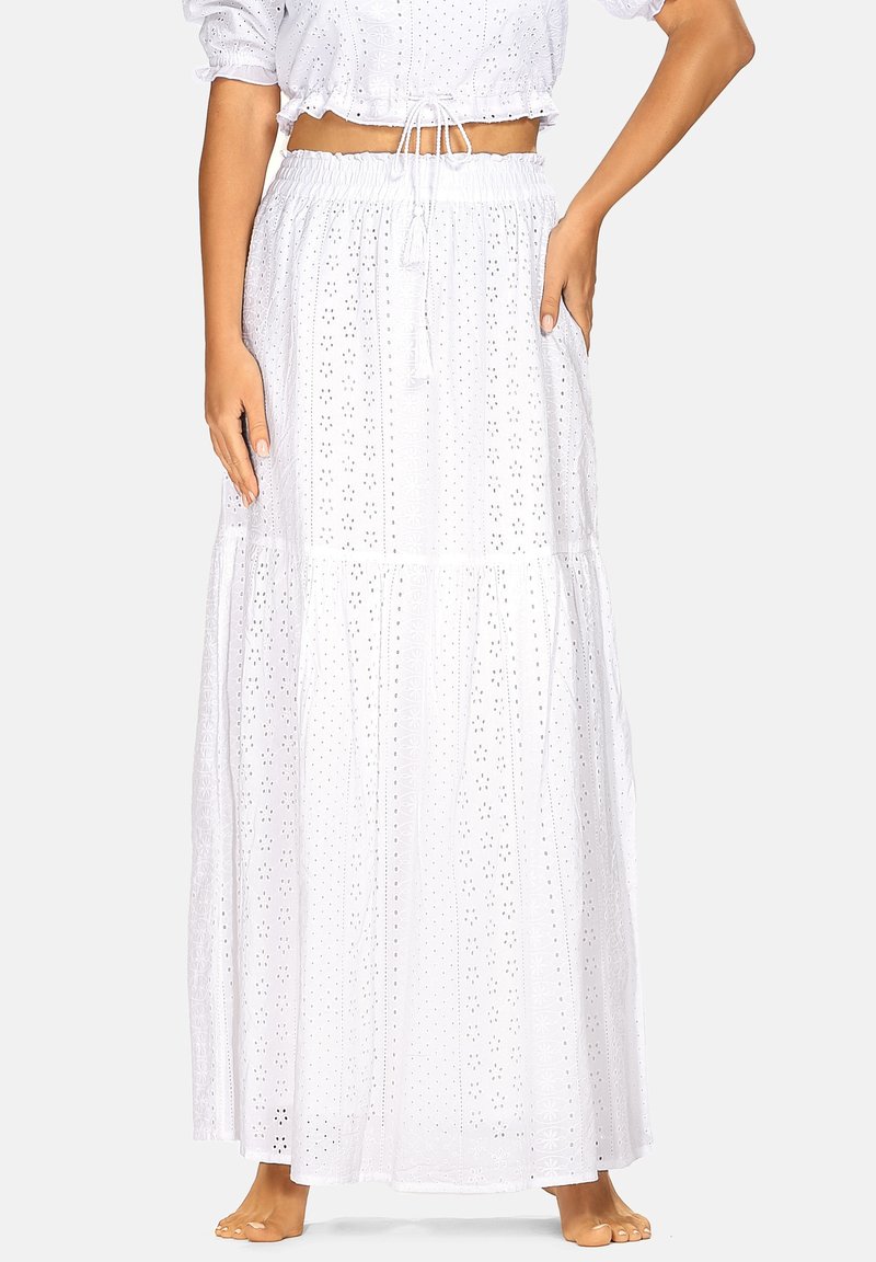Biała maxi spódnica z lekkiego materiału, z wycięciami w kształcie oczek, elastycznym pasem i warstwowym krojem. Łączona z krótkim, obcisłym topem.