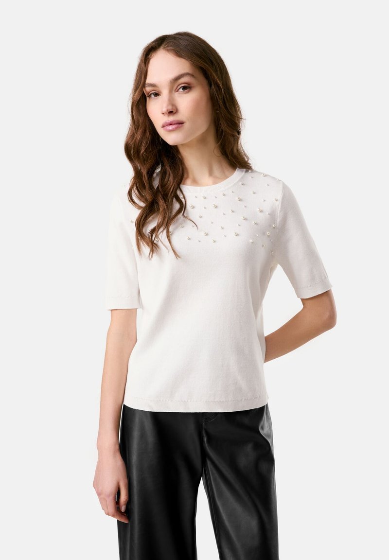 Weißer kurzärmeliger Pullover mit Rundhalsausschnitt, der auf der Vorderseite ein strukturiertes Muster aus kleinen Perlen aufweist. Glattes Strickmaterial und lockere Passform.