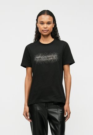 T-shirt en coton noir à manches courtes, avec un design de logo à pois argentés sur le devant. Assorti avec un pantalon en cuir.