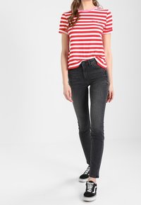 Röd- och vitrandig t-shirt med kort ärm och rund halsringning, kombinerad med mörkgrå slim-fit jeans och svarta sneaker.