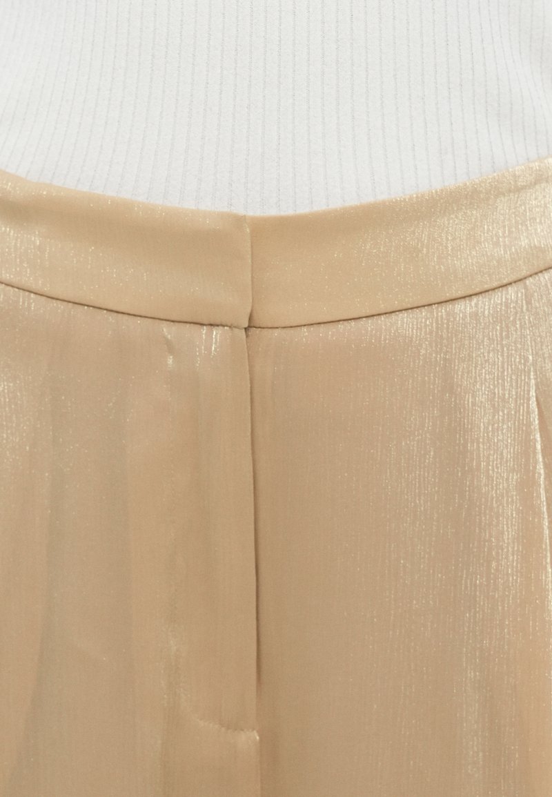 Beige Plisséhose aus glänzendem Material, mit glatter Textur und subtiler Lichtreflexion, hoher Taille und einer Naht vorne.