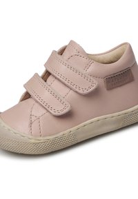 Pale pink leather sneaker with two Velcro straps, textured rubber sole, and a rounded toe design. Features a subtle brand label accent.