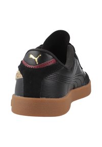 Sneaker in pelle nera con superficie testurizzata, suola di gomma scura, accento bordeaux vicino al tallone e logo dorato sul retro.