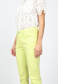 Ljust gula, slim-fit byxor med en mjuk textur, knappknäppning och diskret logodetalj. Matchas med en vit ögla topp.