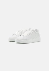 Witte leren sneakers met een gladde textuur, ronde neus en vetersluiting. Bevat subtiele accenten en een dikke, gestructureerde rubberen zool.