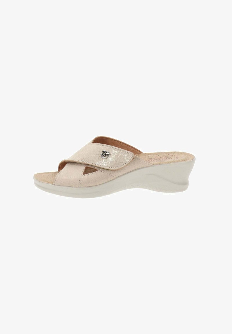 Sandalia de cuña en suave cuero color beige con un diseño de correas cruzadas, punta abierta y un pequeño acento metálico en la parte superior. Plantilla texturizada.
