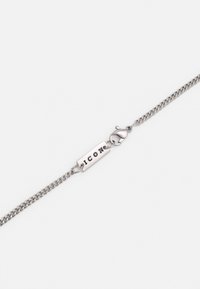  pulseira de cadeia de prata com um design texturizado, apresentando um pendente retangular com a inscrição "ICON" gravada. Fecho de mola. Acabamento metálico suave.