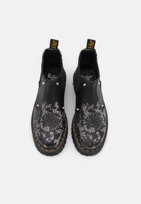Black leather ankle boots featuring a textured snakeskin pattern, silver studs, and yellow stitching along the sole. Round toe design.