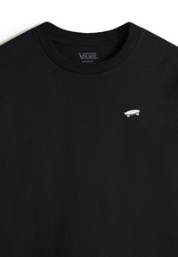 Zwarte losse-fit T-shirt van katoen, met een kleine witte skateboardafbeelding op de linkerborst. Eenvoudige ronde halslijn.