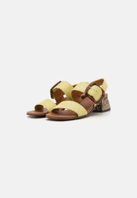 Gule tekstil sandaler med en brun læderfodseng, der har to brede stropper og en skildpadde-mønstret spænde, på en tekstureret blokhæl.