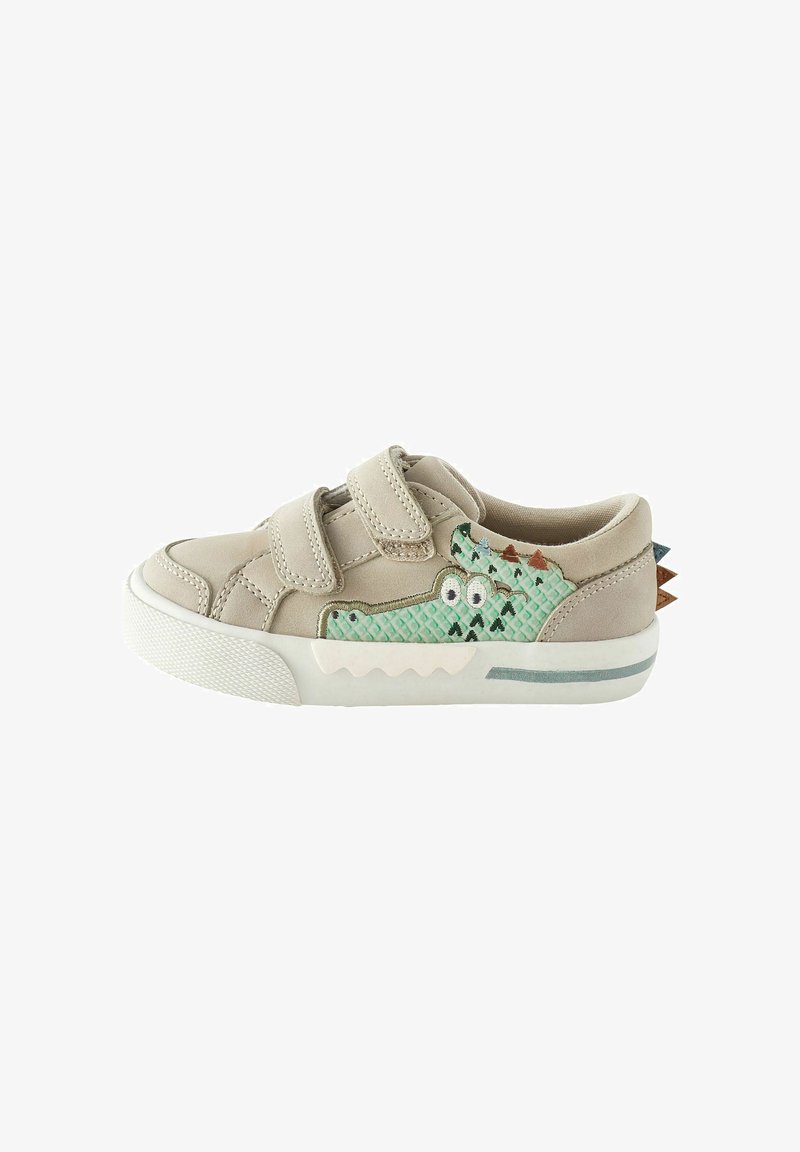 Scarpa beige con strappi in velcro. Presenta un accento in coccodrillo verde testurizzato con occhi e motivi triangolari. Suola bianca con dettagli grigi.