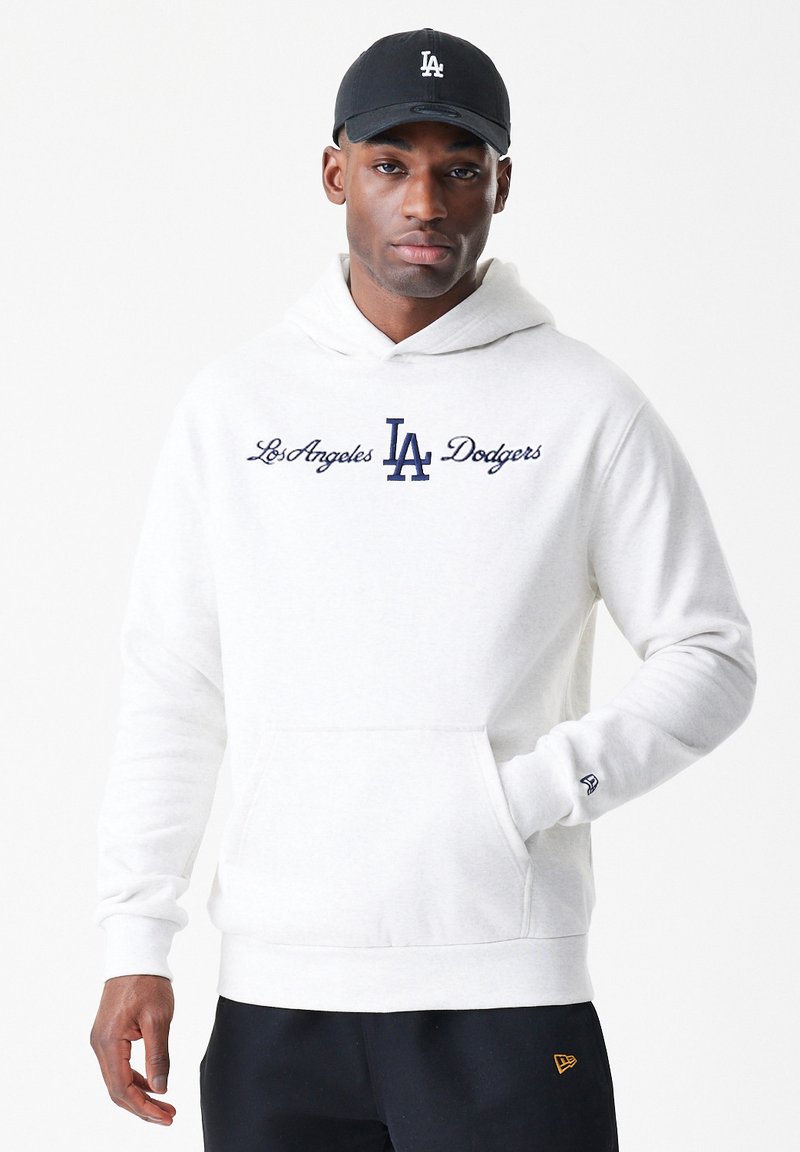 Sweatshirt branca com texto bordado azul-marinho "Los Angeles Dodgers" e logótipo. Apresenta um bolso tipo canguru e punhos canelados, usado com um boné preto.