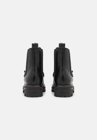 Bottines en cuir noir avec une semelle en caoutchouc robuste, dotées de panneaux élastiques à l'avant et de languettes à l'arrière pour un enfilage facile.