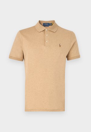 Beige polo krekls, izgatavots no mīksta materiāla, ar trīs pogu aizdari, īsām piedurknēm un mazu izšūtu logo kreisajā krūtī.