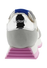 Achteraanzicht van een grijs-witte sneaker met een roze ribbelzool en "victoria" gedrukt op de witte hieltab onder een blauwe trekstrap.
