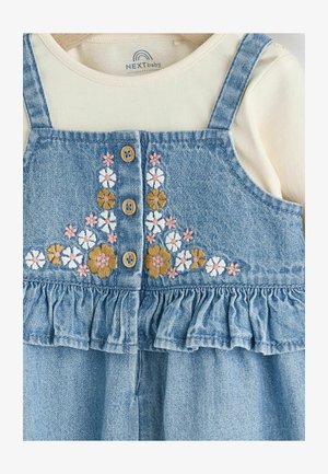 Denim ruha virágos hímzéssel rózsaszínben, sárgában és fehérben, fából készült gombokkal és fodros aljjal. Krém színű blúzra rétegezve.