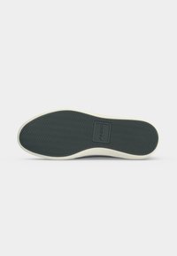 Semelle de chaussure avec motif chevron noir et logo ALDO au centre, entourée d'un liseré blanc.