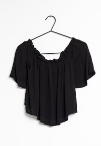 Svart off-shoulder-blus med korta ärmar, med en volangkantad halsringning och lätt, strukturerad tyg. Hänger från en svart krok.