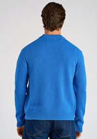 Blauer Strickpullover mit Rundhalsausschnitt, gerippten Bündchen und Saum, mit weicher Textur und figurbetonter Silhouette.