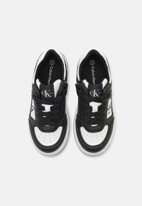 Sneaker bianco e nero con tomaia in pelle e tessuto, punta rotonda, lacci piatti e dettaglio con logo. Suola imbottita per il comfort.