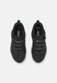 Svarta träningsskor med meshmaterial, blåa accenter och runda snören. Designen inkluderar vadderade kragar och en texturerad sula.