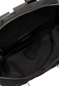 Black fabric backpack with a zippered closure, featuring a spacious interior, smooth lining, and an inner zip pocket for organization.