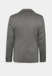 Černo-bílý kostkovaný blazer s klopovým límcem, dvěma knoflíky na rukávech a přiléhavým střihem s rozparky na zadní straně.