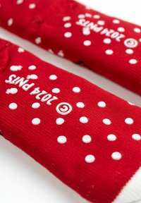Calze rosse con pois bianchi, superficie texturizzata e un logo. Il design include una combinazione di sezioni solide e a fantasia.