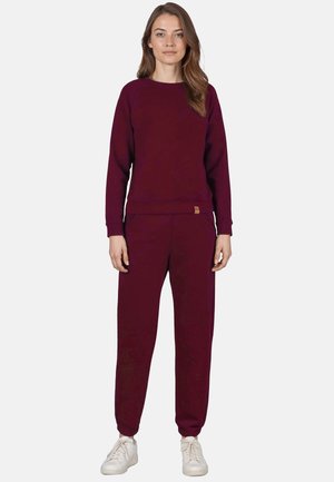 Bordeauxfarbener Sweatshirt und passende Jogginghose aus weichem Stoff, mit Rundhalsausschnitt und elastischen Bündchen, kombiniert mit weißen Sneakers.