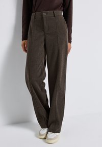 Bruna rutiga högmidjade byxor har en rak passform, knäppning framtill och är kombinerade med vita sneakers för en avslappnad stil.