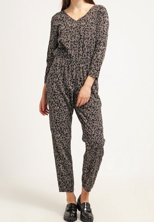 Leopardenmuster-Overall in Braun und Schwarz, aus weichem Material gefertigt. Mit V-Ausschnitt, langen Ärmeln und elastischem Taillenbund. Flache Schuhe.