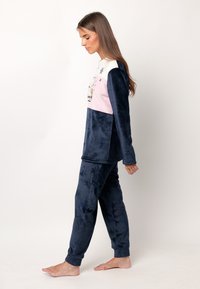 Conjunto de pijama de forro polar en azul marino con una parte superior a rayas en blanco y rosa. Presenta un diseño bordado y un ajuste relajado, completo con pantalones con puños.