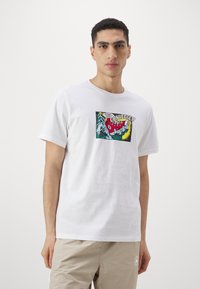 Camiseta blanca de algodón con un gráfico colorido estilo cómic en la parte frontal que presenta la palabra "CONVERSE!!" y un diseño de mano.