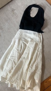 Abito senza maniche in bianco e nero con scollatura rotonda, caratterizzato da un top aderente e una gonna plissettata fluida realizzata in tessuto leggero.