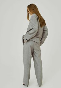 Completo grigio con pantaloni a vestibilità ampia e blazer oversize, realizzato in tessuto texturizzato con un motivo sottile e dettagli con bottoni.