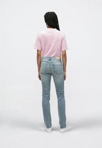 Ροζ κοντομάνικο t-shirt σε ανοιχτή απόχρωση, σε συνδυασμό με ανοιχτόχρωμο τζιν παντελόνι με λογότυπο στο πίσω μέρος, μπροστινές τσέπες και ελαστικότητα.