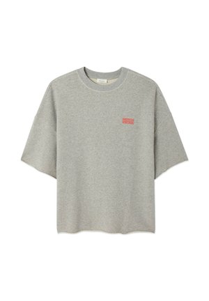 Pelēka kokvilnas T-krekls ar īsām piedurknēm, kreisajā krūtīs ar sarkanu "AMERICAN VINTAGE" grafiku. Ikdienišķa, ērtā piegriezumā.