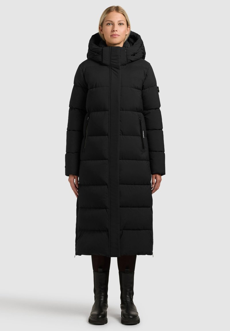 Manteau long matelassé noir avec capuche, doté d'une fermeture éclair, de coutures verticales et de deux poches latérales. Tissu texturé avec une finition lisse.